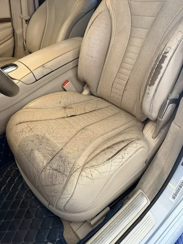 Beige driver seat with worn leather before repair